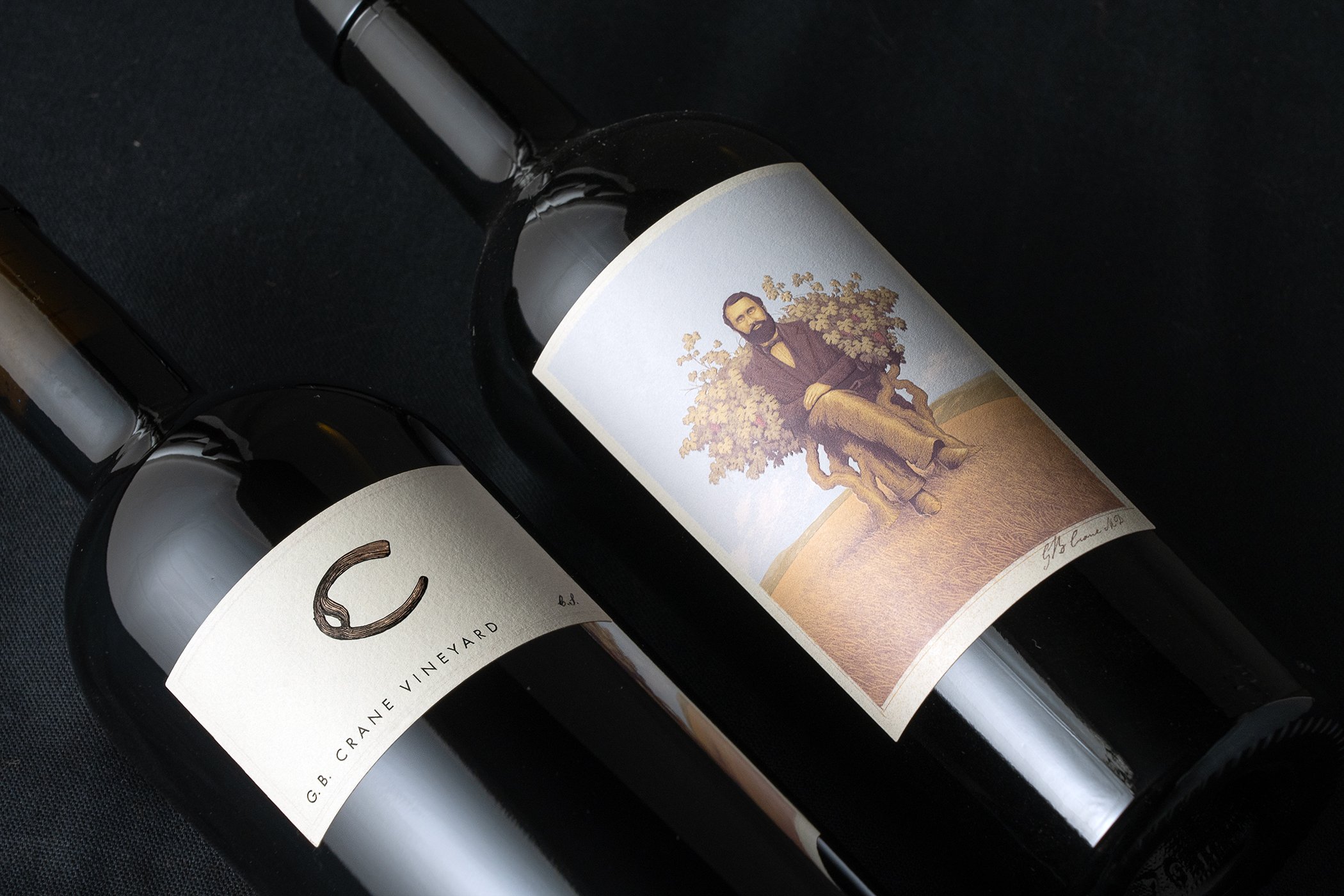 Close-up of wine bottles lying on a surface, showing their labels with artwork of a man sitting under a tree.